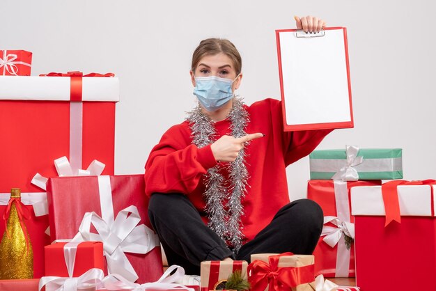 Jovem mulher sentada de frente para os presentes de Natal