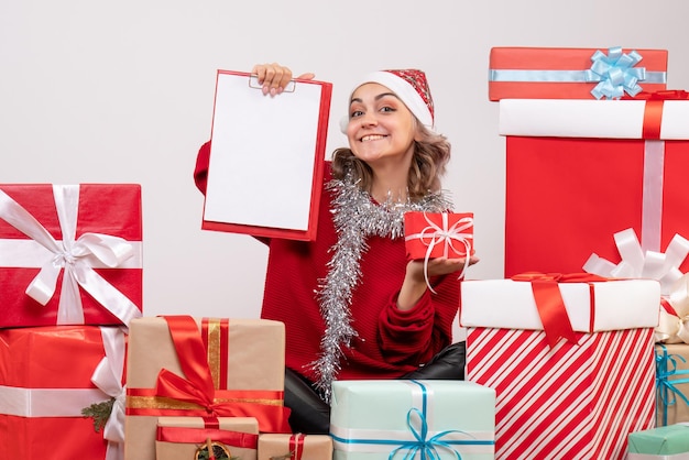 Jovem mulher sentada de frente para os presentes de Natal