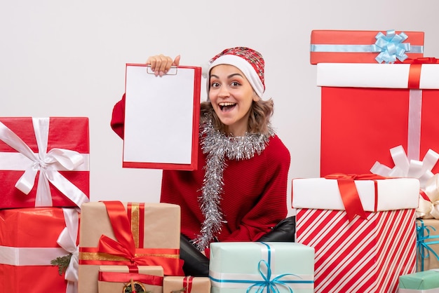 Jovem mulher sentada de frente para os presentes de Natal