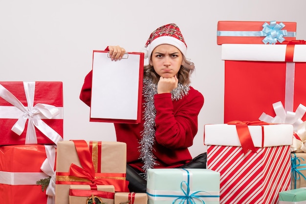 Jovem mulher sentada de frente para os presentes de natal