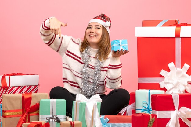 Jovem mulher sentada em frente aos presentes de Natal