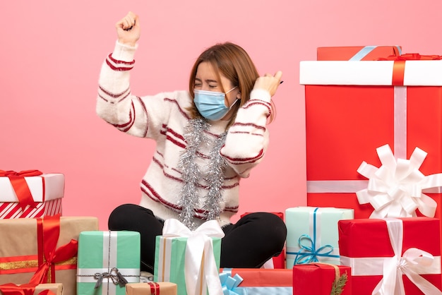 Jovem mulher sentada em frente aos presentes de Natal