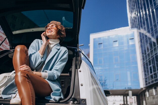 Jovem mulher sentada na parte de trás do carro falando ao telefone