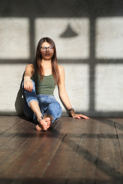 Jovem mulher sentada no chão de uma sala vazia