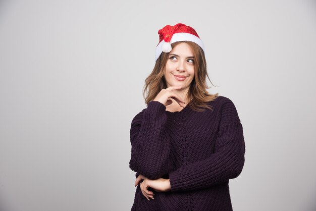 Jovem mulher sorridente com chapéu de Papai Noel em pé e posando.