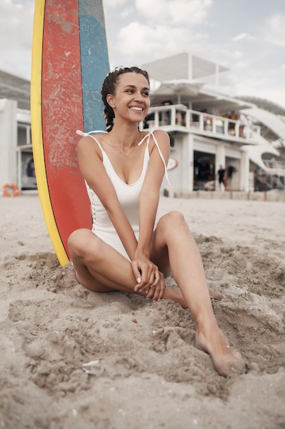 Jovem mulher sorridente com prancha de surf ao ar livre