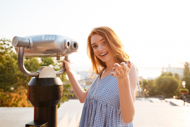 Jovem mulher sorridente em pé no telescópio