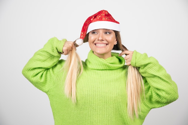 Jovem mulher sorridente, posando com chapéu vermelho de Papai Noel.