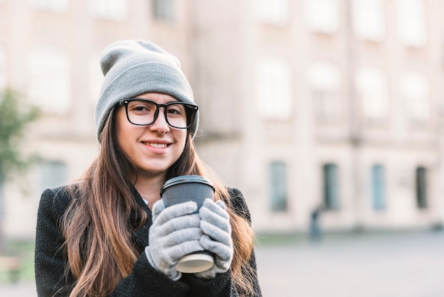 Foto grátis jovem mulher sorridente segurando a taça de bebida na rua