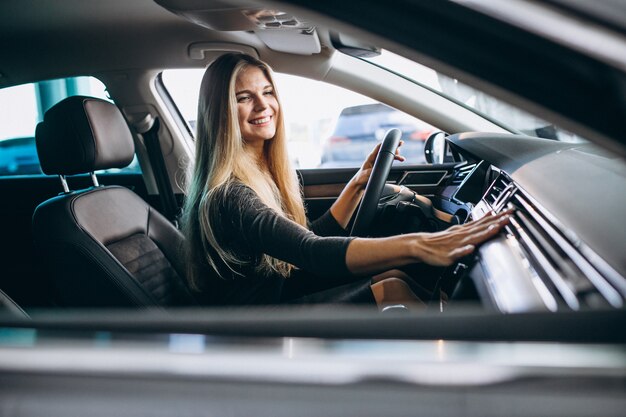 Jovem mulher testando um carro em uma sala de exposições