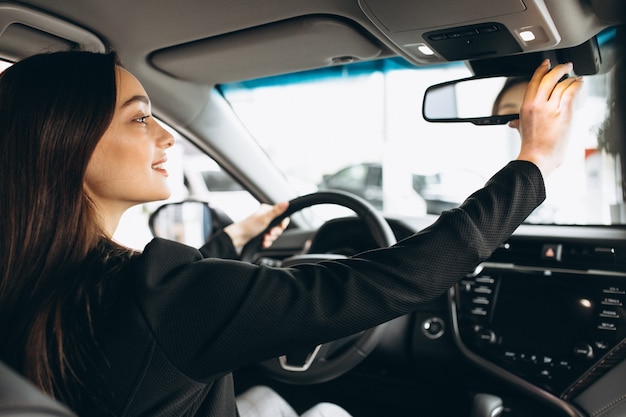 Jovem mulher testando um carro em uma sala de exposições