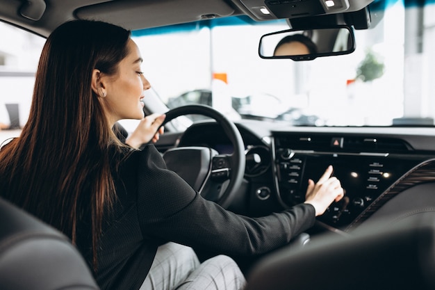 Jovem mulher testando um carro em uma sala de exposições