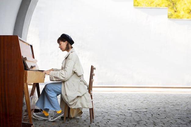 Foto grátis jovem mulher tocando piano ao ar livre com espaço de cópia