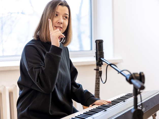 Jovem mulher tocando piano sentada em frente ao microfone