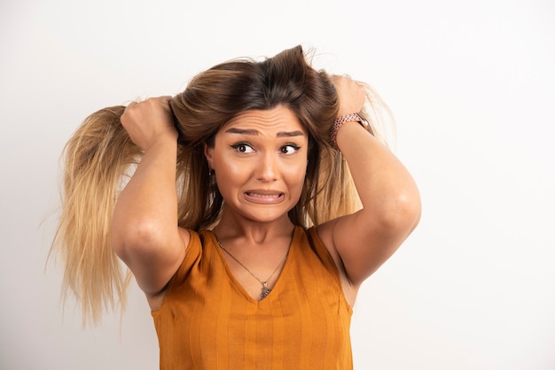 Foto grátis jovem mulher tocando seu cabelo e posando em fundo branco.