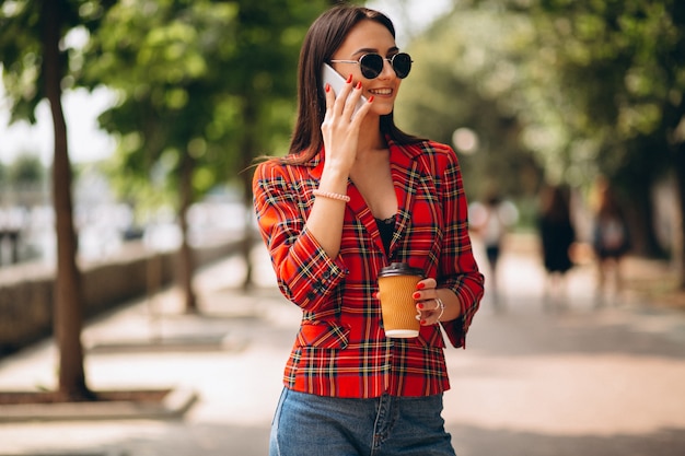 Jovem mulher tomando café e falando ao telefone