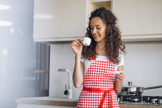 Jovem mulher tomando café na cozinha pela manhã