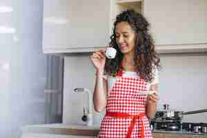 Foto grátis jovem mulher tomando café na cozinha pela manhã