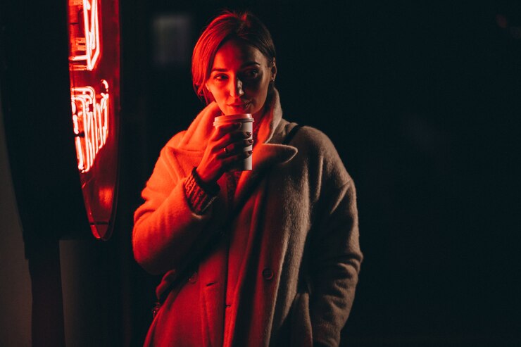 Foto grátis jovem mulher tomando café na rua à noite