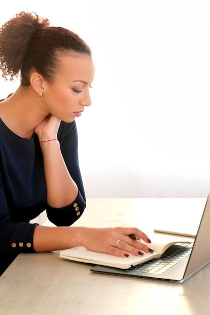 Foto grátis jovem mulher trabalhando com laptop e agenda