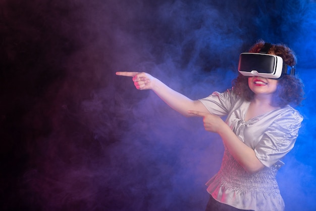 Jovem mulher usando fone de ouvido de realidade virtual em superfície azul escura