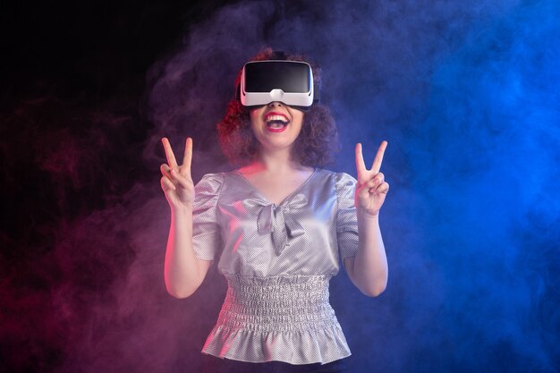 Jovem mulher usando fone de ouvido de realidade virtual em uma superfície azul escura