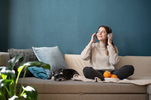 Foto grátis jovem mulher usando fones de ouvido no sofá