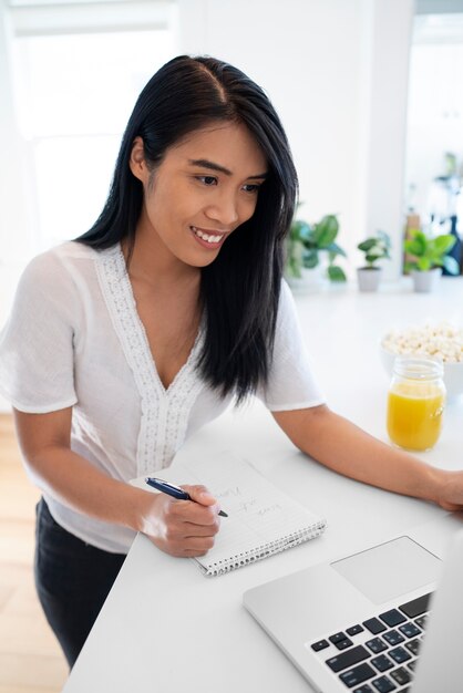 Jovem mulher usando laptop e notebook com caneta para anotações