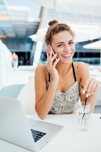 Jovem mulher usando smartphone em uma cafeteria ao ar livre.