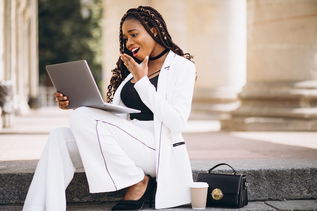 Jovem mulher vestida de branco usando laptop