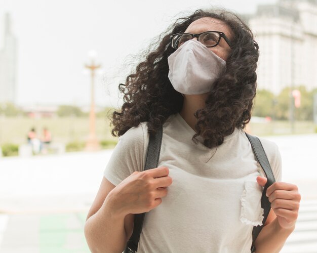 Jovem mulher vestindo uma máscara médica enquanto olha para cima