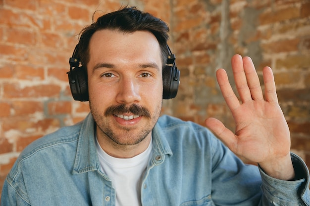 Foto grátis jovem músico com fones de ouvido cumprimentando o público antes de um show online ou passagem de som em casa