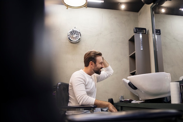 Jovem na barbearia após cortar o cabelo