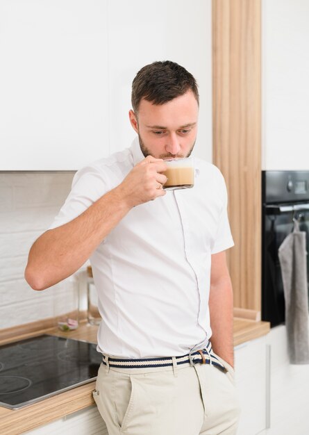 Jovem na cozinha bebendo um cappuccino