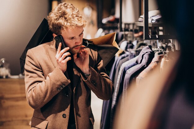 Jovem na loja de moda masculina, falando ao telefone