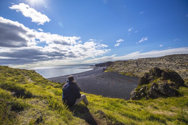 Jovem nas belas praias de pedra da península de Snaefellsnes em um mirante natural