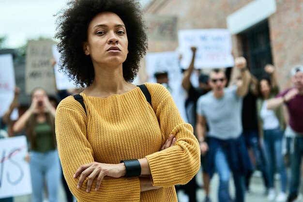 Jovem negra confiante com braços cruzados participando de um protesto pelos direitos humanos