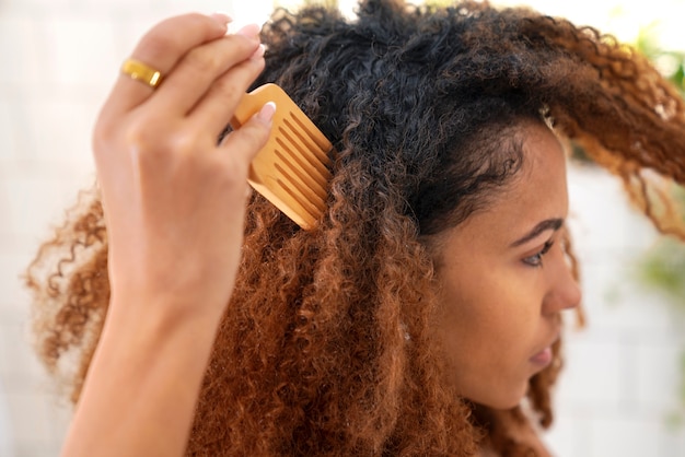 Jovem negra cuidando do cabelo afro