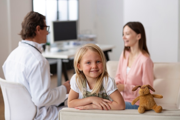 Jovem no pediatra para uma consulta com o médico e a mãe