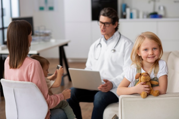 Foto grátis jovem no pediatra para uma consulta com o médico e a mãe