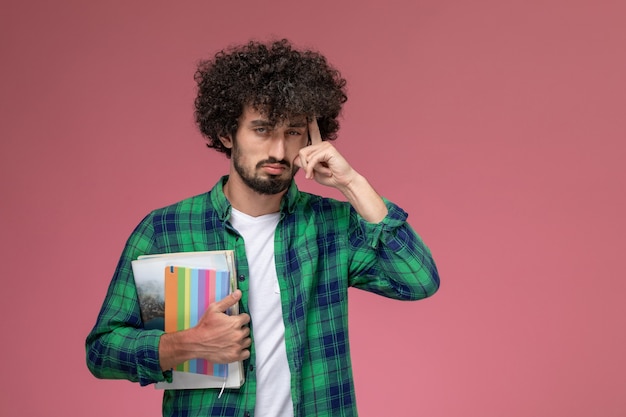 Jovem olhando de frente pensando sobre algo com notebooks