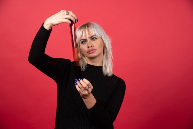 Jovem olhando em uma fita fotográfica em um fundo vermelho. Foto de alta qualidade