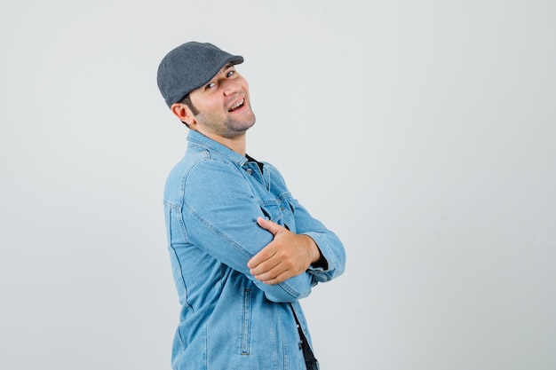 Jovem olhando para o lado enquanto sorria de jaqueta, boné e parecendo otimista.