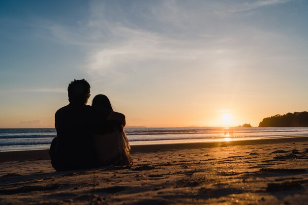 Jovem, par asiático, observar, pôr do sol, perto, praia, doce, par, feliz, relaxe, desfrute, amor, e, momento romântico