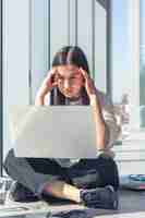 Foto grátis jovem pensativa na frente de uma tela de laptop no escritório perto da janela