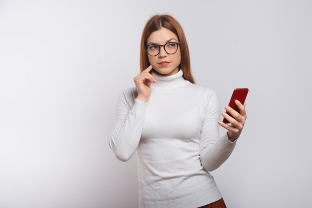 Foto grátis jovem pensativa segurando smartphone