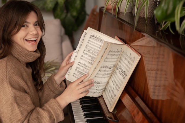 Jovem pianista alegre sentada ao piano folheando as notas