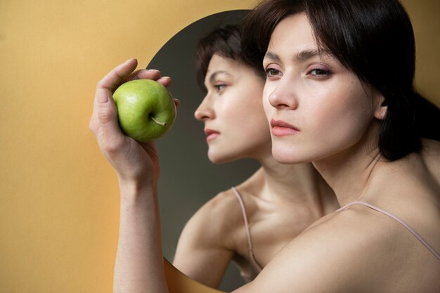 Jovem posando ao lado do espelho com maçã