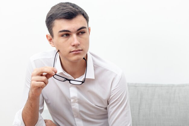 Jovem posando com óculos na mão