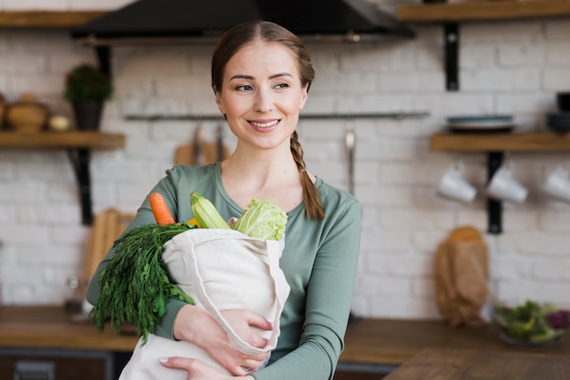 Jovem positiva, segurando o saco com legumes orgânicos